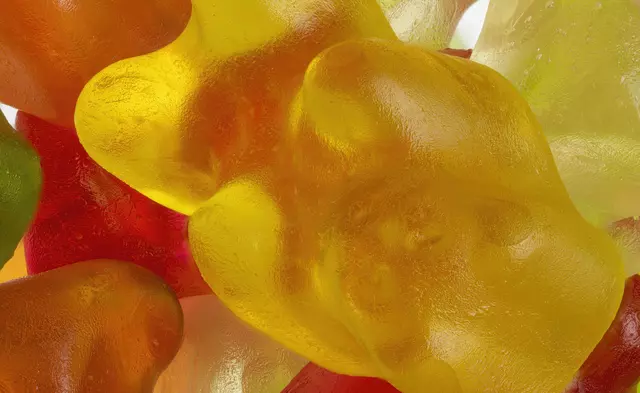 Group of four adults in sportswear laughing and stacking hands outdoors in a sunny park