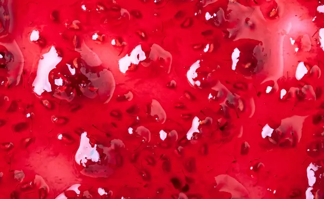 Close-up of glossy red strawberry jam with visible seeds and chunks.